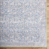 Close-up of the Crevan Washable Area Rug showing a traditional denim and tan pattern on a light wood floor. Swatch