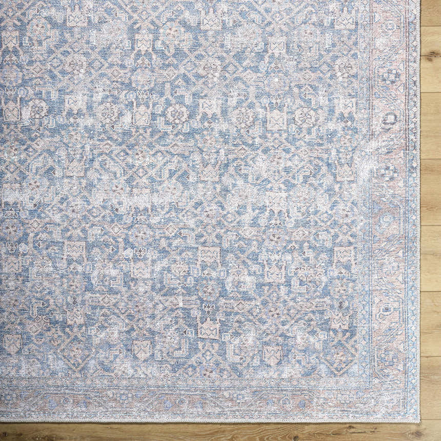 Close-up of the Crevan Washable Area Rug showing a traditional denim and tan pattern on a light wood floor. Swatch