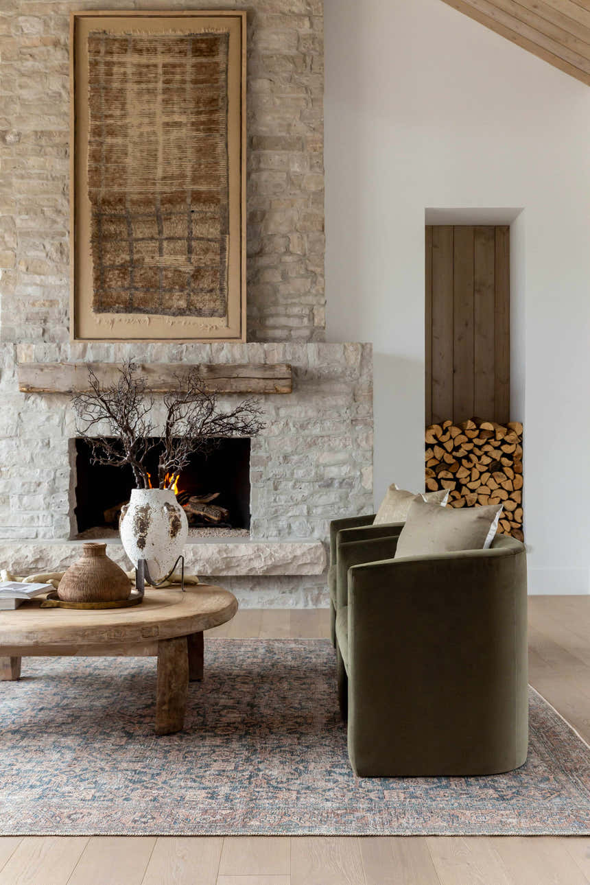 Living room scene with a stone fireplace and the Crevan Washable Area Rug in dark red, denim, light sage, tan, and teal. Roomscene-Rectangle