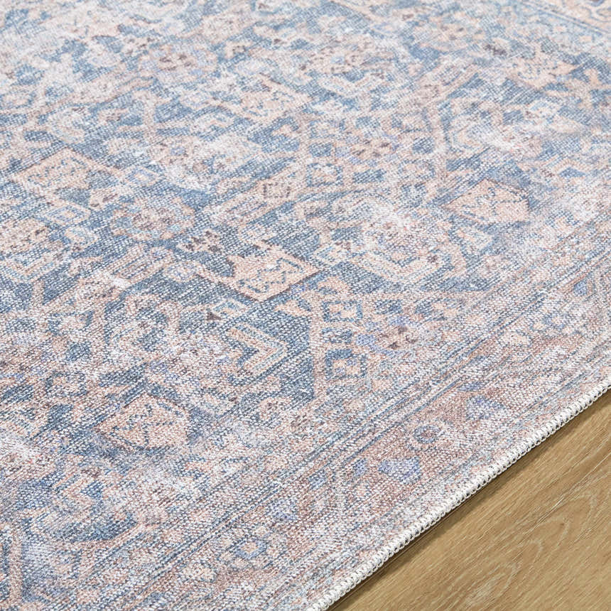 Close-up of the Crevan Washable Area Rug, featuring a traditional pattern in denim, tan, and light sage colors. Texture