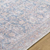 Close up of the Lorelai Vivir x LIVABLISS rug, a machine woven rug with a traditional dark red, denim, and tan pattern. Texture