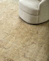 Close-up of the tan Fetscher V Vintage Damask Area Rug with a neutral round chair on top. Styleshot