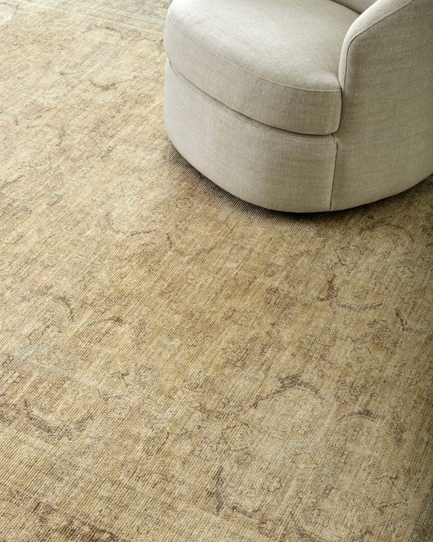 Close-up of the tan Fetscher V Vintage Damask Area Rug with a neutral round chair on top. Styleshot