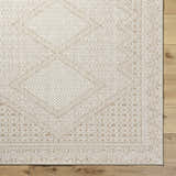 Close-up of the Chaman Area Rug showing its tan and white geometric pattern and woven texture on a wood floor. Corner