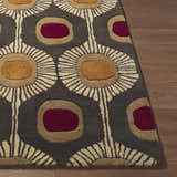 Close-up of the Canovanas Modern Wool Rug, featuring a floral pattern in brown, burgundy, tan, and dark brown on a wood floor. Front