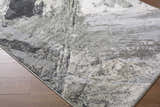 Close-up of the Chaeli Area Rug showing its beige, black, ivory, and charcoal contemporary pattern and machine-woven texture. Corner