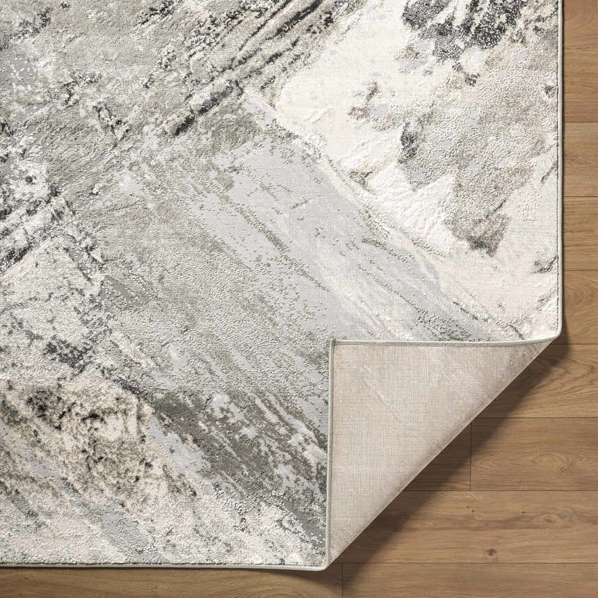 Close-up of the Chaeli Area Rug showing its beige, black, charcoal, and ivory abstract pattern and machine-woven texture. Fold