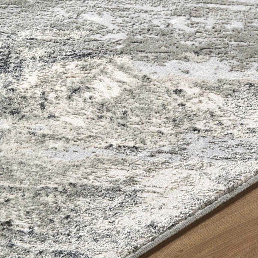 Close-up of the Chaeli Area Rug showing its abstract beige, black, charcoal, and ivory pattern and machine-woven texture. Texture