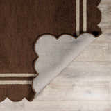 Close-up of the hand-tufted Chogan Chocolate Brown Area Rug with a scalloped edge and two beige stripes. Wool texture. Fold
