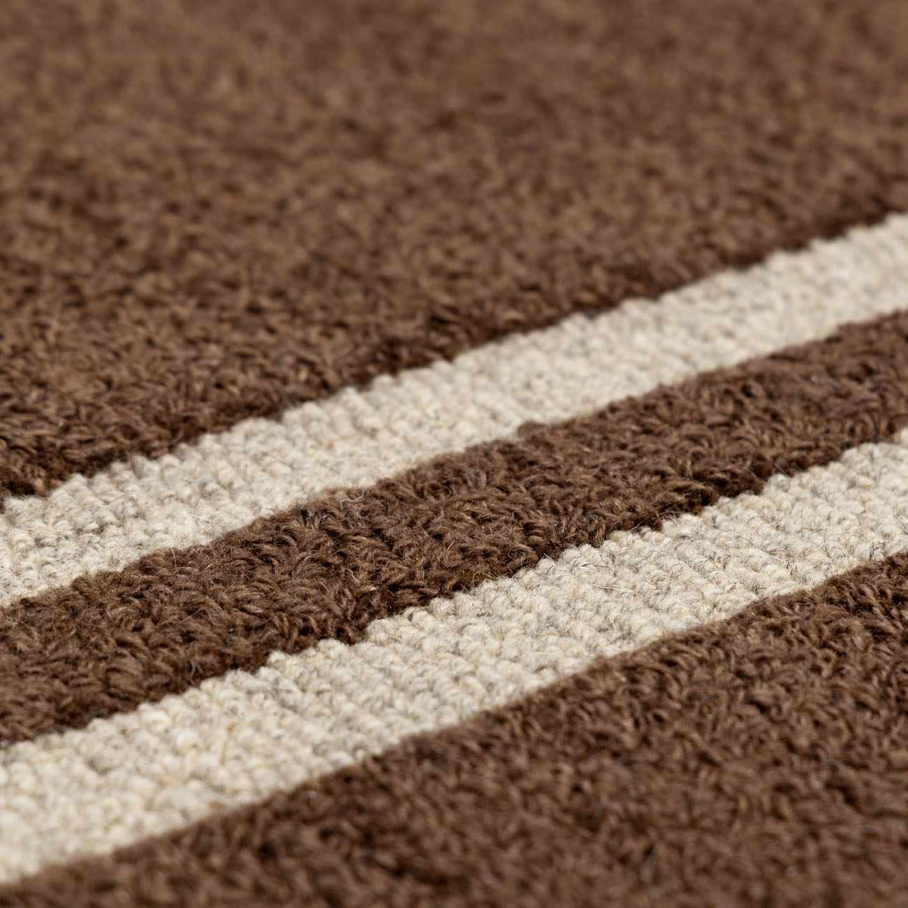 Close-up of the wool Chogan Chocolate Brown Area Rug showing brown and beige stripes and textured, hand-tufted construction. Texture