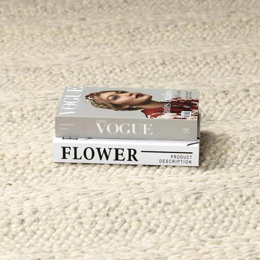 Close up of the Clarke Textured Braided Stripe - Dark Beige Area Rug showing texture and braided design with stacked books. Styleshot