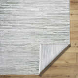 Close-up of the Corwin 3D Striped Washable Area Rug. Cream, gray, and sage stripes on a textured polyester rug. Fold