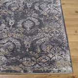 Close-up of the Alexei Area Rug showing its charcoal, gray, tan, and black traditional pattern and soft texture. Front