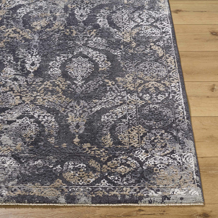 Close-up of the Alexei Area Rug showing its charcoal, gray, tan, and black traditional pattern and soft texture. Front