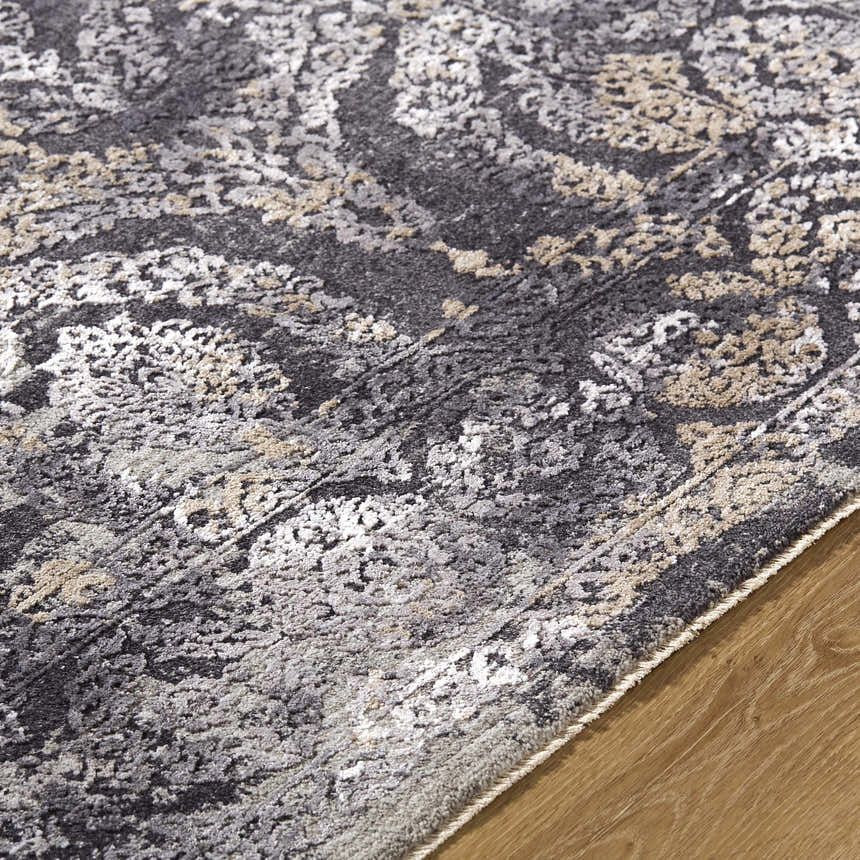 Close-up of the Alexei Area Rug showing its black, charcoal, gray, and tan traditional pattern and soft polyester texture. Texture