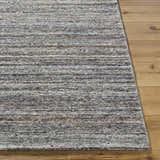 Close-up of the hand-tufted Capote Tan Area Rug showing its ash, charcoal, and tan tones and textured wool design. Front