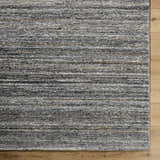 Close up of the hand tufted Capote Tan Area Rug showing ash, charcoal, and taupe colors and wool texture. Corner