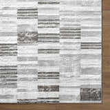 Close-up of the contemporary Chiaki Light Gray Area Rug with ivory, silver, and medium gray geometric pattern. Corner