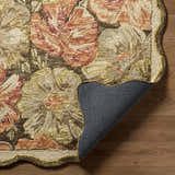 Close-up of the hand-tufted Campos Area Rug. Floral pattern in shades of cream, green, brown, and peach. Wool texture. Fold
