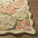Close-up of the hand-tufted Campos Area Rug. Wool rug has a floral design in peach, cream, and green hues with a scalloped edge. Front