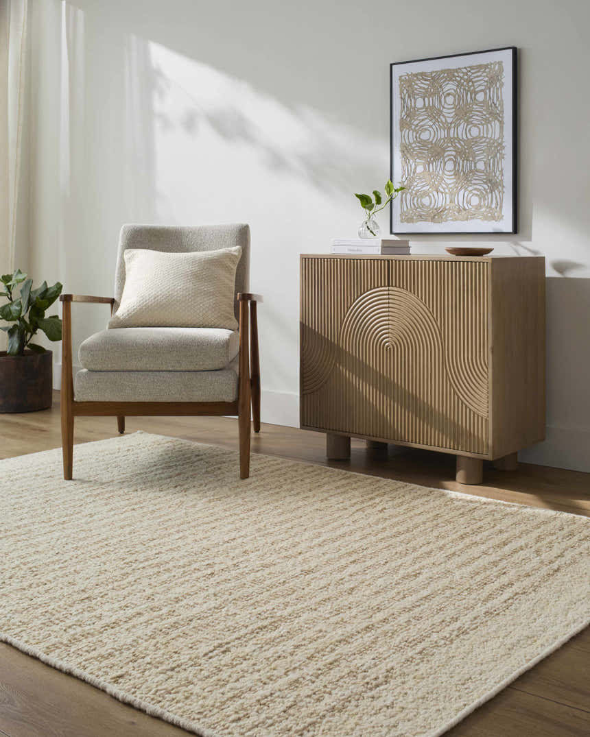 Living room scene with a neutral Arlais Striped Area Rug, gray chair, and wood cabinet with modern art. Roomscene-Rectangle