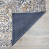Close-up of the Dagatan Washable Area Rug showing beige, black, and camel oriental pattern and blue backing on light wood floor. Fold
