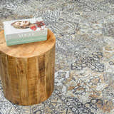 Close-up of Dagatan Washable Area Rug in beige, black, and camel with a traditional oriental pattern and a wood side table. Styleshot