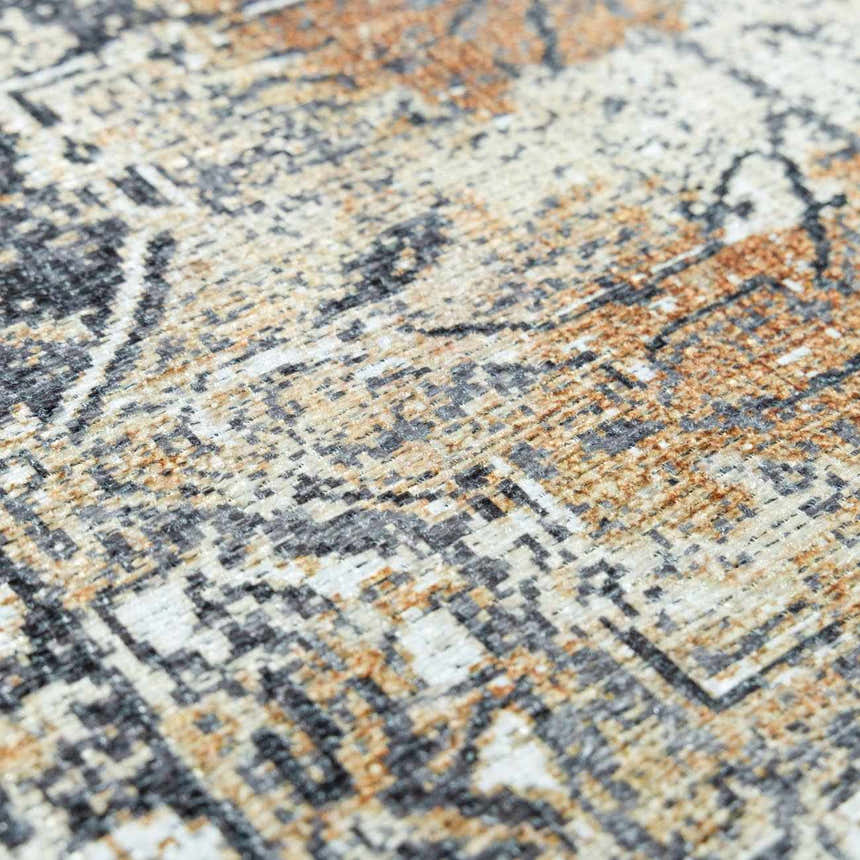 Close-up of the Dagatan Washable Area Rug. Beige, black, and camel farmhouse style rug with an oriental pattern. Texture