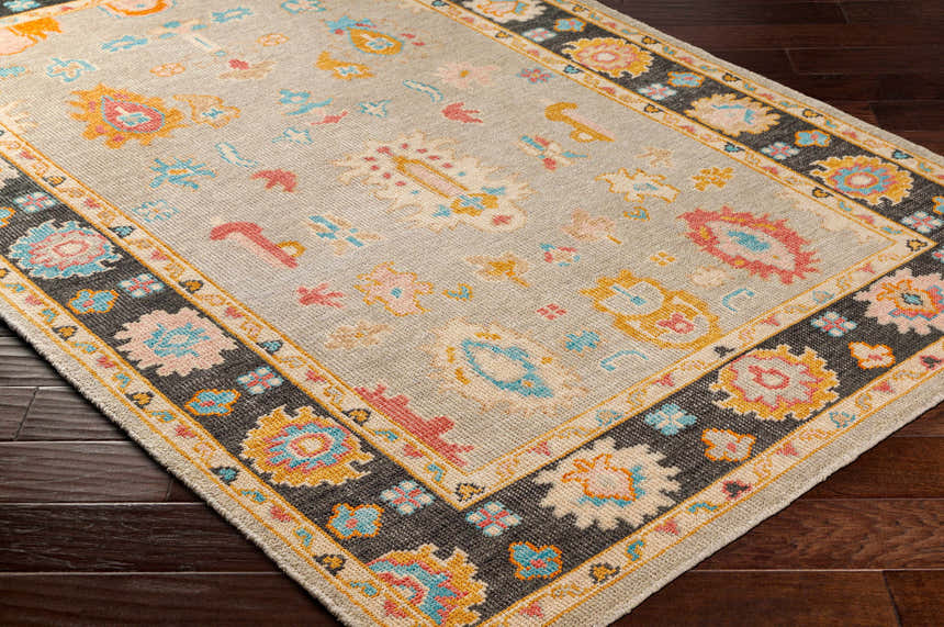 Close-up of the hand-knotted Dalupaon Area Rug. Features a traditional floral design with black, beige, blue, and pink hues. Corner
