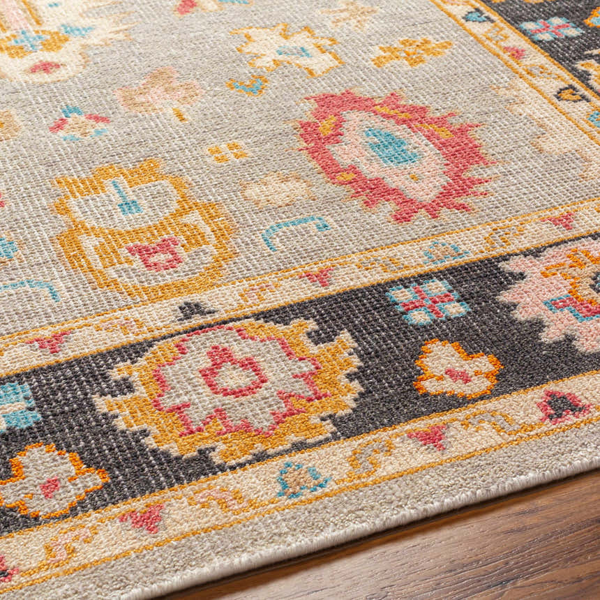 Close-up of the hand-knotted Dalupaon Area Rug. Features a traditional floral pattern in black, beige, pink, blue, and mustard tones. Texture