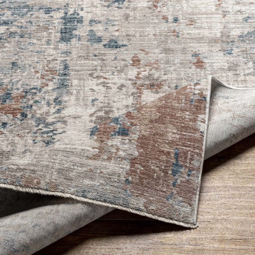 Close-up of the Danlugan Area Rug showing its charcoal, cream, brown, and blue contemporary pattern and machine-woven texture. Fold