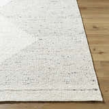 Close-up of the Ethara Ivory Charcoal rug showing its wool texture and subtle global pattern on a wood floor. Front