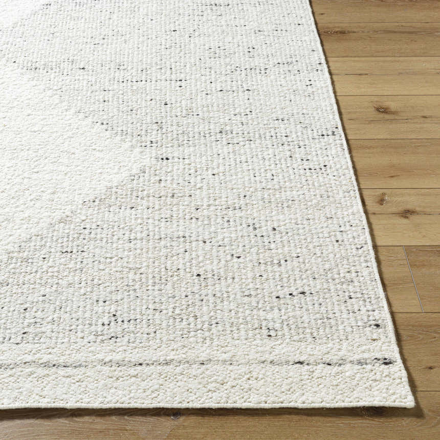 Close-up of the Ethara Ivory Charcoal rug showing its wool texture and subtle global pattern on a wood floor. Front