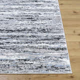Close-up of the Azmina Area Rug featuring a contemporary black, ivory, blue, and gray abstract design. Front
