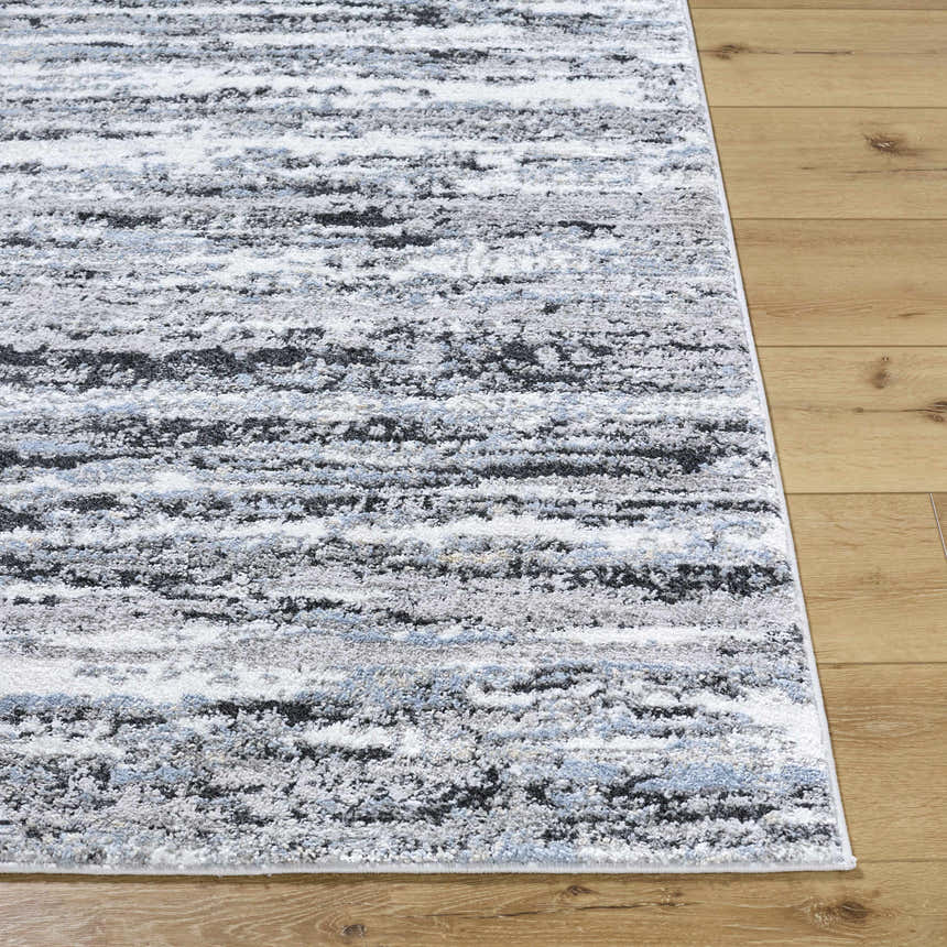 Close-up of the Azmina Area Rug featuring a contemporary black, ivory, blue, and gray abstract design. Front