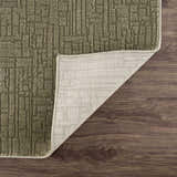 Close-up of the Leanna Green Washable Area Rug showing its geometric design, texture, backing, and green color. Fold