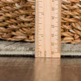 Close-up of the Leanna Green Washable Area Rug showing pile height with a ruler on a wood floor next to a woven basket. Pile