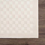 Close-up of the Gaiwan Cream Washable Area Rug showing a subtle checkerboard pattern and soft texture on a wood floor. Corner