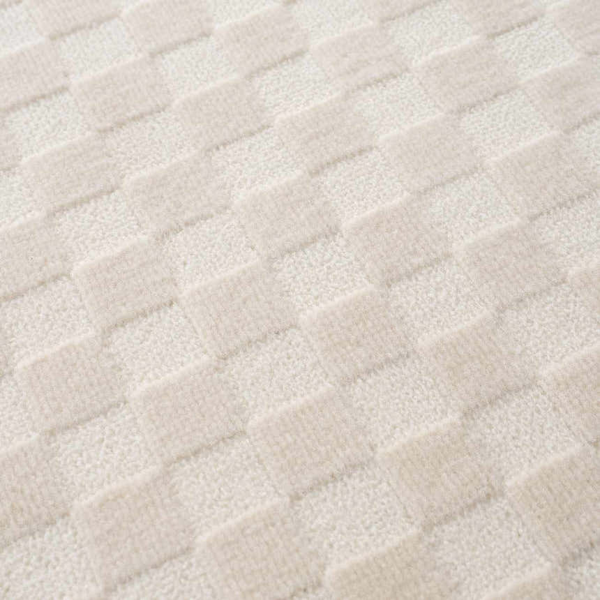 Close-up of the Gaiwan Cream Washable Area Rug featuring a subtle checkerboard pattern with cream and off-white tones. Texture