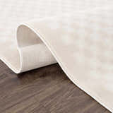 Close-up of the Gaiwan Cream Washable Area Rug showing its subtle square pattern and soft texture on a wood floor. Fold