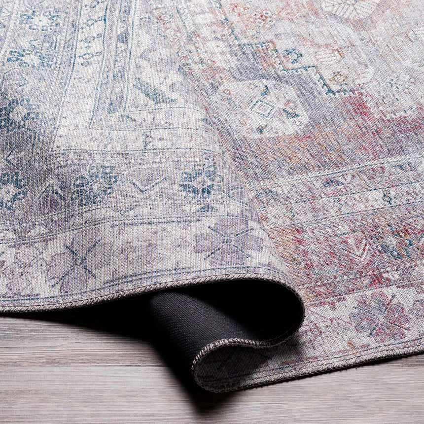 Close-up of the Livabliss Colin rug showing its farmhouse style, traditional pattern, and colors: charcoal, cream, dark red, and gray. Fold