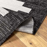 Close-up of the black, charcoal, and off white geometric New Djugun Area Rug showing its machine-woven texture. Fold