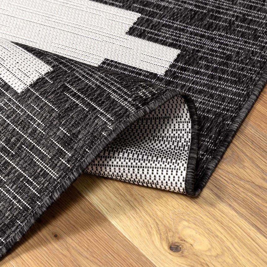 Close-up of the black, charcoal, and off white geometric New Djugun Area Rug showing its machine-woven texture. Fold