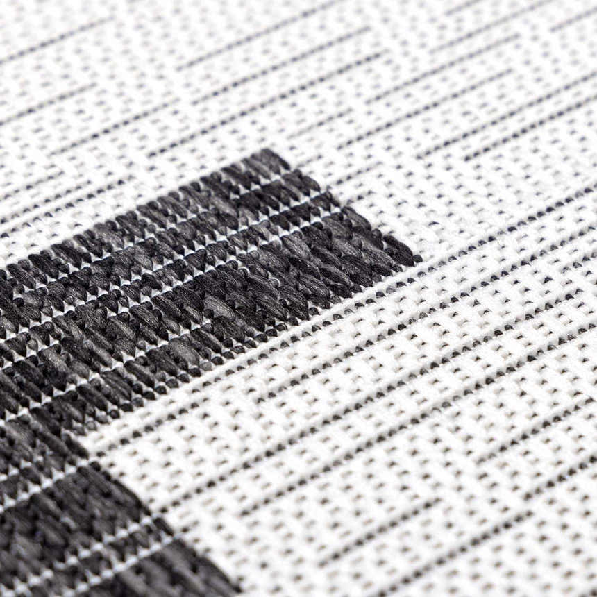 Close-up of the Djugun Area Rug. Black and off-white geometric pattern with a woven texture. Texture