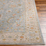 Close up of Livabliss Avant Garde AVT-2371 rug showing floral pattern in dark brown, gray, mustard, and taupe on wood floor. Front