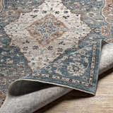 Close-up of the Edremit Area Rug showing its cream, blue, and brown traditional, oriental pattern and soft, machine-woven texture. Fold