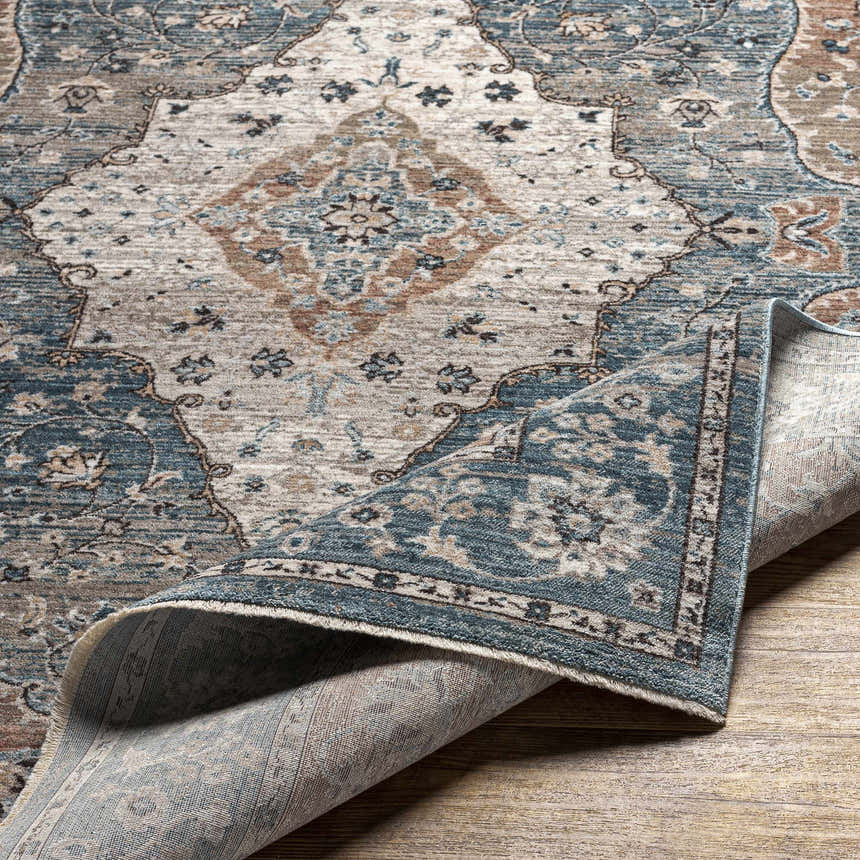 Close-up of the Edremit Area Rug showing its cream, blue, and brown traditional, oriental pattern and soft, machine-woven texture. Fold