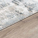 Close-up of Eltham Thick Luxe Rug in dusty sage, light gray, and navy on light wood flooring. Contemporary style. Corner