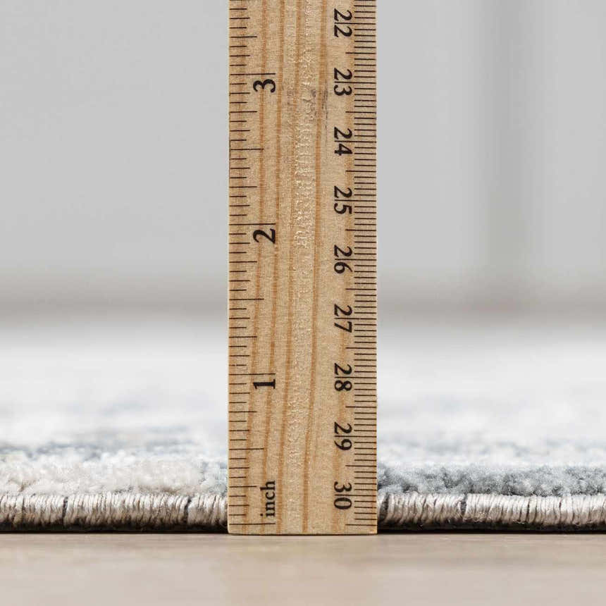 Close-up of Eltham Thick Luxe Rug showing its plush pile height with a ruler. Dusty Sage and Light Gray colors. Pile