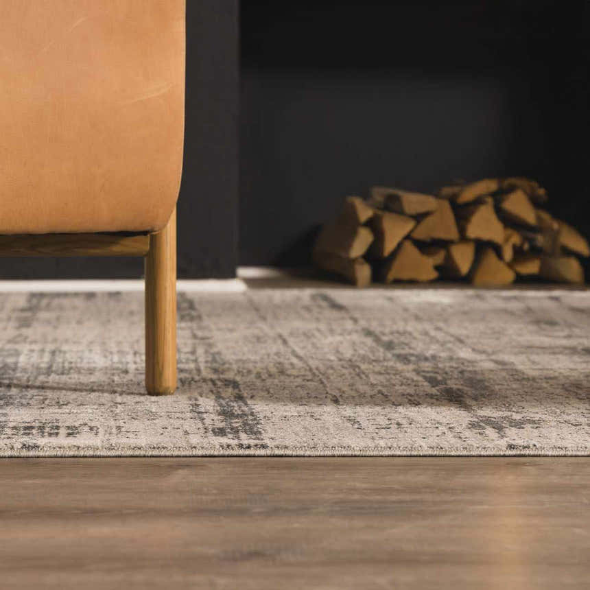 Living room scene with a light gray Eltham Thick Luxe Rug, tan leather chair, and stacked firewood by a black fireplace. Roomscene-Rectangle
